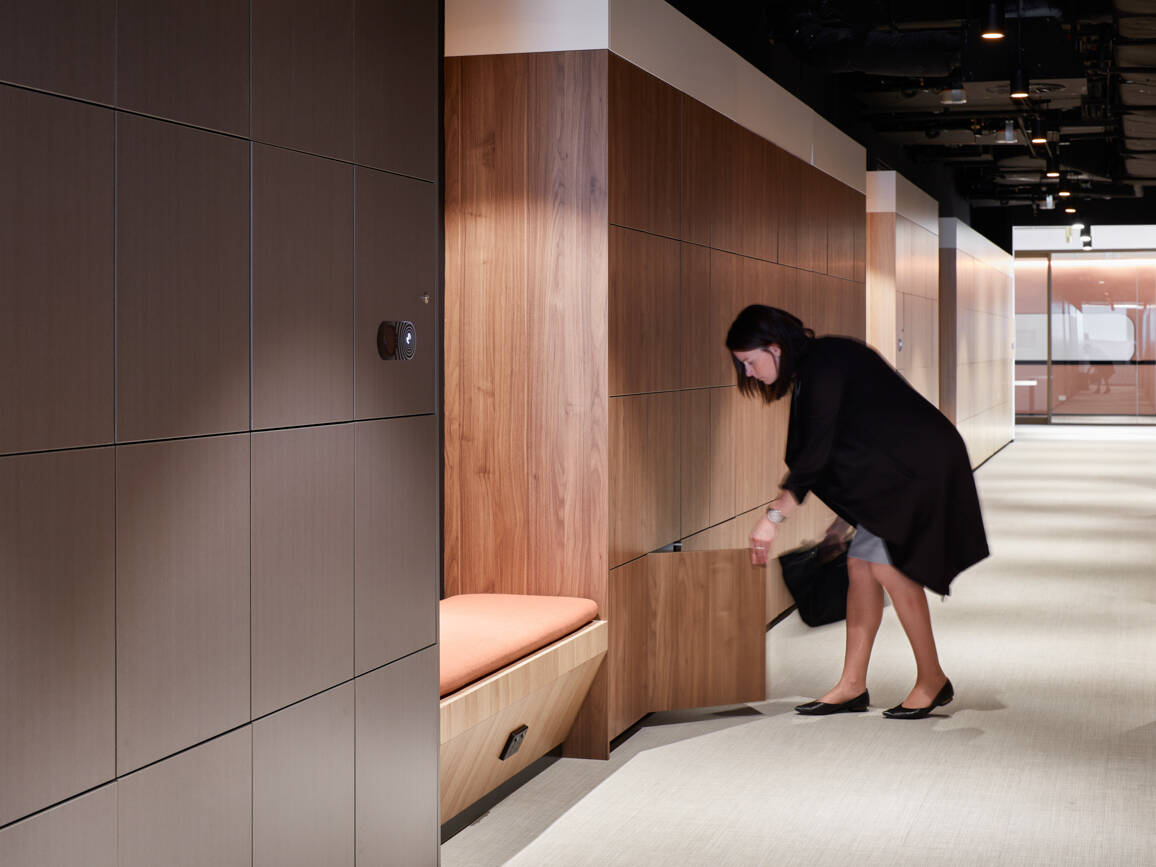 Wood Laminate Lockers in office environment with woman putting bag into locker